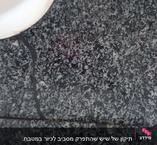 תיקון ומילוי סדק במשטח שיש כהה סמוך לכיור